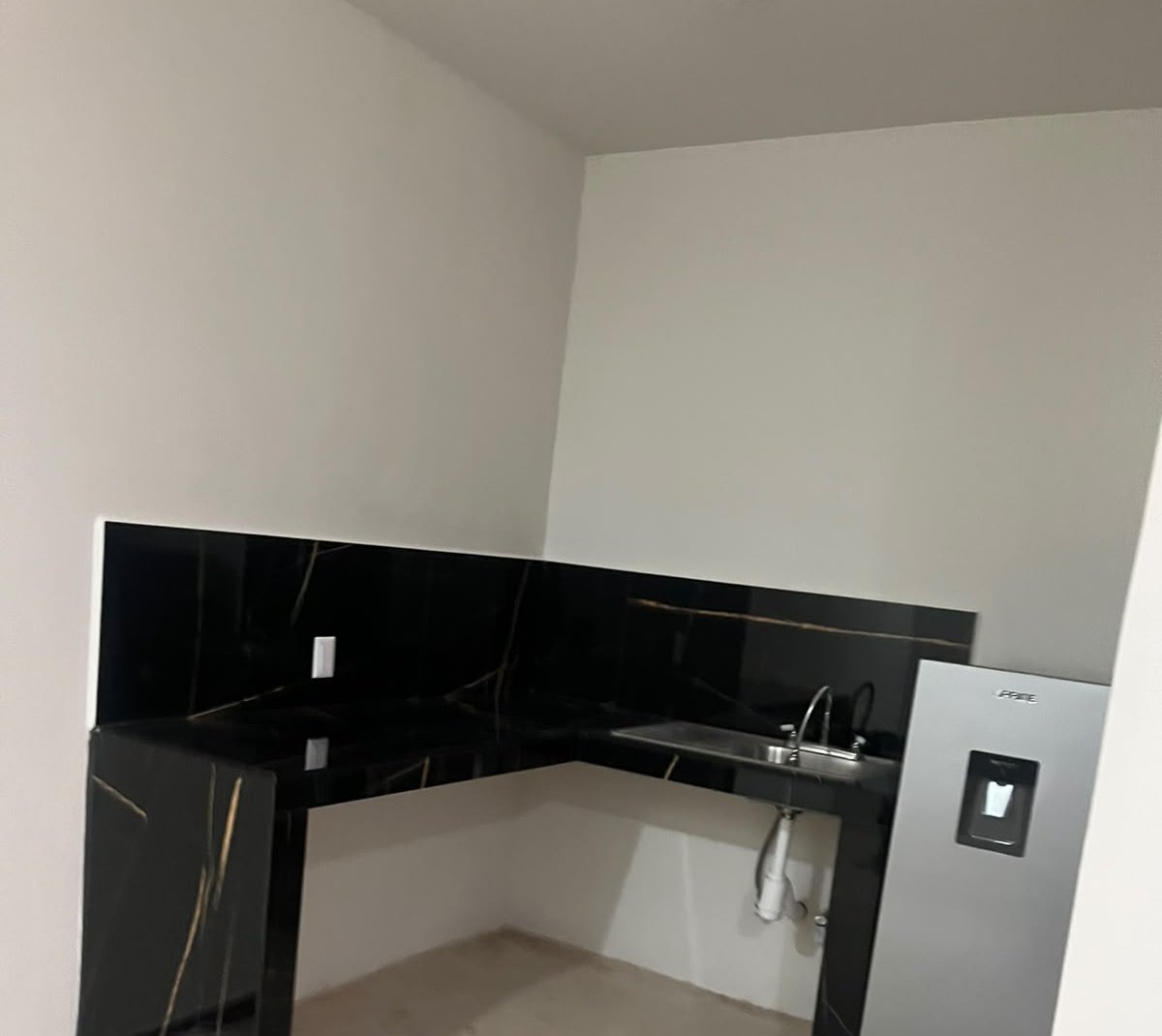 Cocineta con cubierta de mármol negro y refrigerador